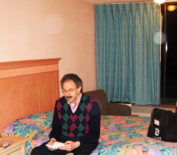 Man sitting on a hotel bed, with circular light spots (angel orbs) in the photograph