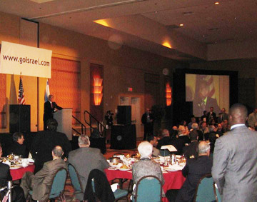 Banquet audience facing a stage and hanging website banner