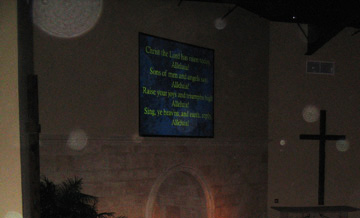 Church cross and projected text, with a circular light spot (angel orbs) on the wall