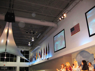 Hall with flags and video screens, with circular light spots (angel orbs) in the photograph
