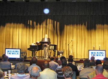 Pianist on a stage with gold curtains, with a blue circular light spot (angel orbs) above