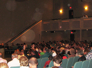 Auditorium crowd with circular light spots (angel orbs) above the balcony