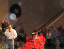 People near a lectern and red flowers, with circular light spots (angel orbs) in the photograph