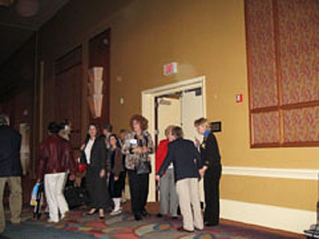 People standing beside an auditorium doorway with circular light spots (angel orbs) near the ceiling