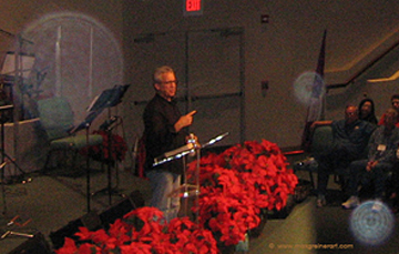 Speaker behind red flowers with translucent circular spots visible nearby