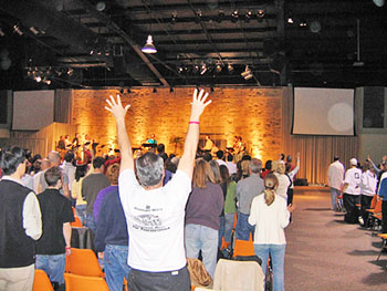 Congregation raising their arms toward an orange-lit stage