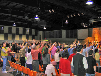 Side view of worshippers raising their hands in an auditorium