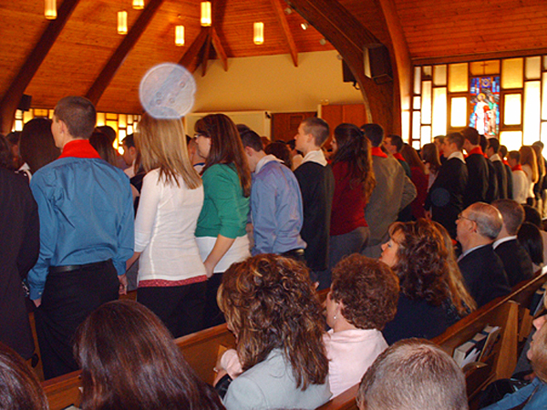 Congregation in a church with wooden ceiling beams, with a large white circular light spot (angel orbs)
