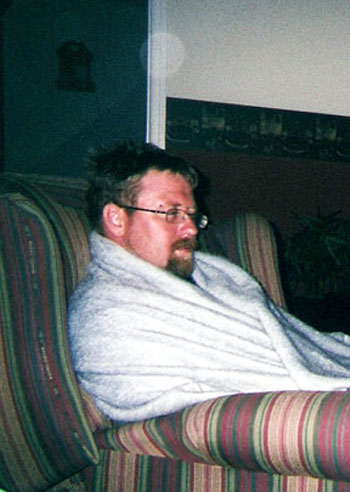 Man seated on a sofa with pale circular light spots (angel orbs) on the wall