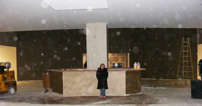 Unfinished indoor space with a person near a counter and many circular spots in the photograph