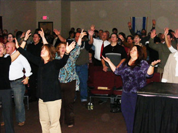 Congregation standing with raised hands indoors