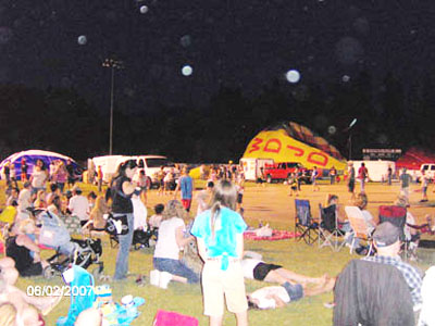Crowd and colorful hot-air balloons at dusk