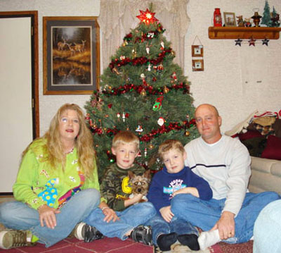 Family posing beside a Christmas tree with circular light spots (angel orbs) visible in the photograph