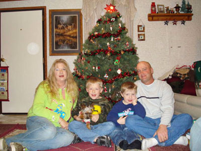 Family posing beside a Christmas tree with circular light spots (angel orbs) visible in the photograph