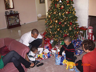 Family gathered around gifts beside a Christmas tree