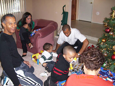 Family gathered around gifts beside a Christmas tree