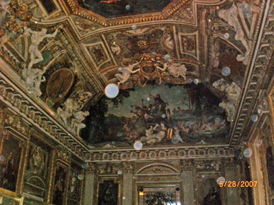 Ornate painted church ceiling with a bright circular spot in the photograph