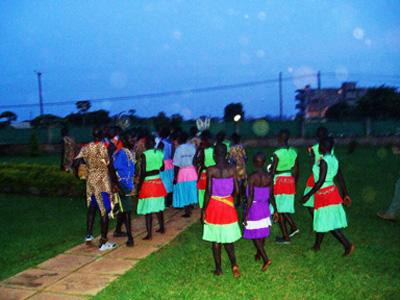 Group in colorful clothing standing outdoors at dusk beneath scattered light spots