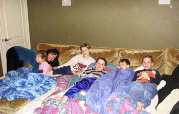 Children resting together beneath blankets on a sofa