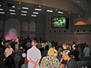 Congregation facing a stage and video screen in a large church