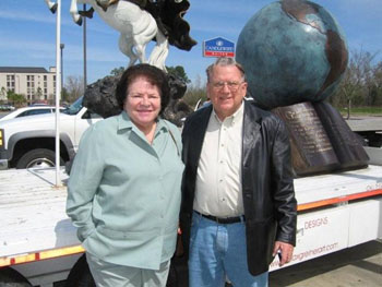 Couple posing beside a globe and mounted-rider sculpture display
