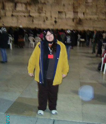 Woman at the Western Wall at night, with a circular light spot (angel orbs) in the photograph
