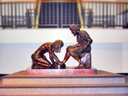 Small Divine Servant® bronze sculpture displayed on a polished base indoors