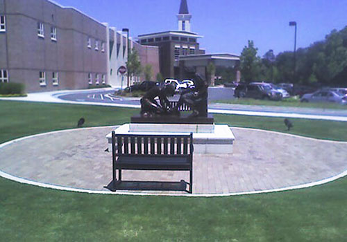 Divine Servant® in a paved courtyard with a bench in front