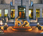Illuminated lion sculpture and circular fountain before a stone building