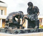 Divine Servant® sculpture on a stone platform outside a building with white columns