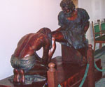 Divine Servant® sculpture displayed indoors behind a rope barrier