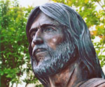 Detail of a bronze bearded face framed by draped fabric