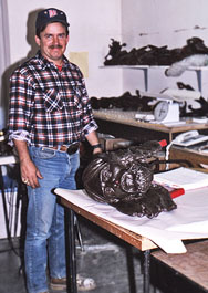 Max Greiner beside a sculpted head on a workbench