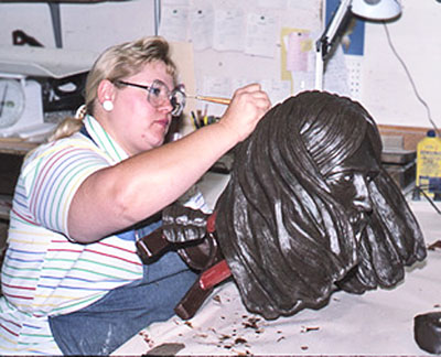 Woman refining the hair on a sculpted head