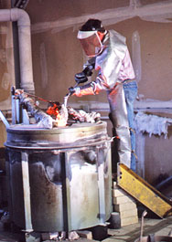 Foundry worker in protective clothing beside a furnace