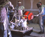 Foundry workers pouring molten metal into sculpture molds