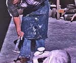 Worker breaking mold material away from a cast component