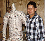 Man beside a life-size figure armature during development of Divine Servant®