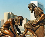 Divine Servant® sculpture with city buildings in the background
