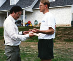 Two men examining a hand pose outdoors as a reference for the sculpture