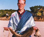 Male model in a draped robe holding a fishing net outdoors