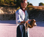 Male model in a draped robe holding a fishing net outdoors