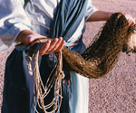 Close-up reference photograph of hands holding a fishing net and rope