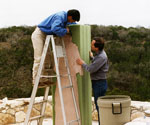 Workers cutting a green foam block around the figure template