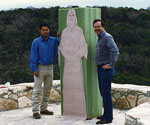 Two workers beside the partly shaped green figure armature