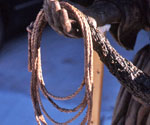 Close-up of the figure's hand holding a loop of rope beside the fishing net