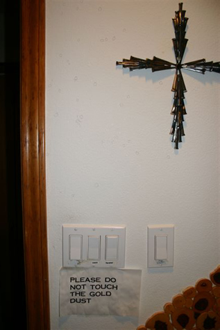 Wall cross above bathroom switches and a handwritten note