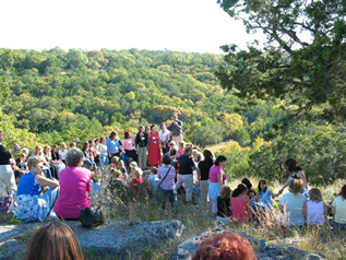 People gathered on a rocky overlook surrounded by wooded hills