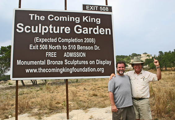Two men beside The Coming King Sculpture Prayer Garden sign
