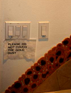 Light switches above a notice asking visitors not to touch the gold dust